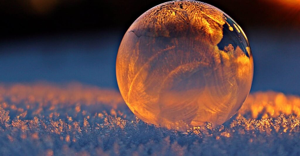 什么是中医的“三因制宜”?最核心的中医辨证思维之一 2 Close-up shot of a frozen bubble with warm reflections resting on a snowy surface at twilight.