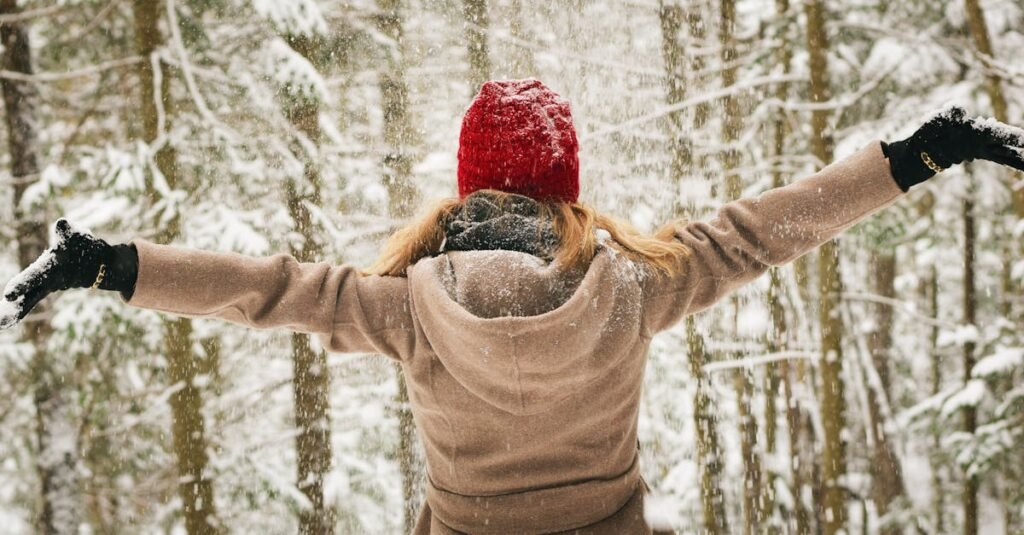 Woman in red hat enjoying a snowy winter day in Lake Placid forest.