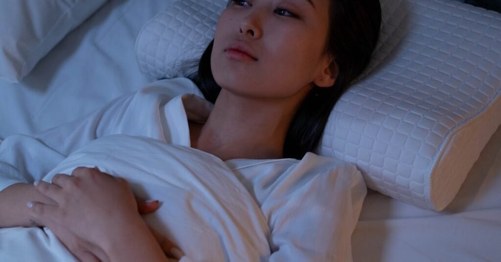 An Asian woman lying awake in bed, reflecting on her thoughts during a sleepless night.